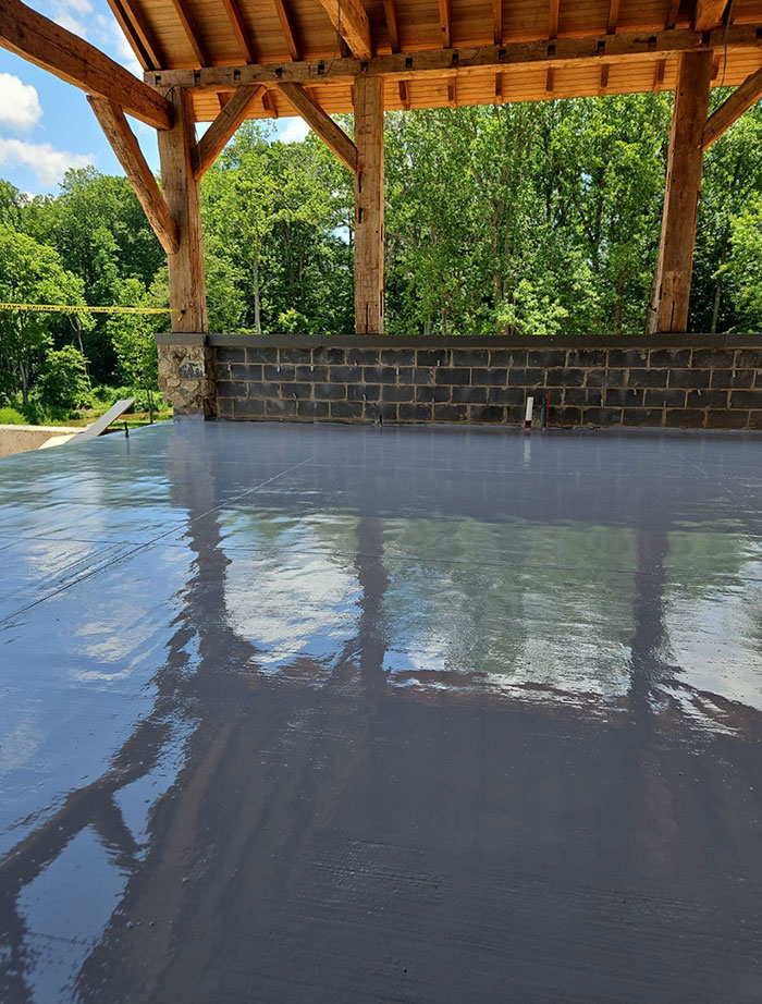 A shiny, freshly coated floor under a wooden pavilion with trees visible in the background.
