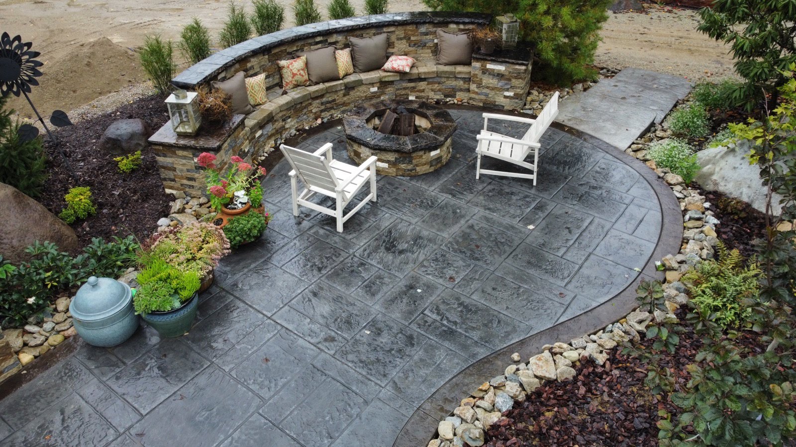 a stamped concrete patio with a fire pit and chairs