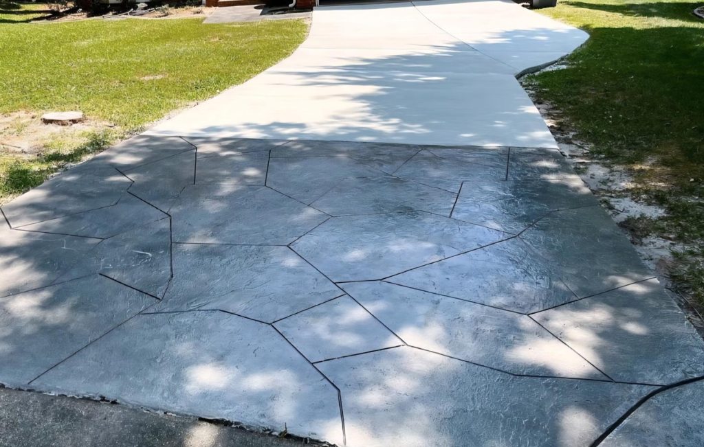 A driveway with a concrete section and a stamped pattern section resembling large irregular stones.