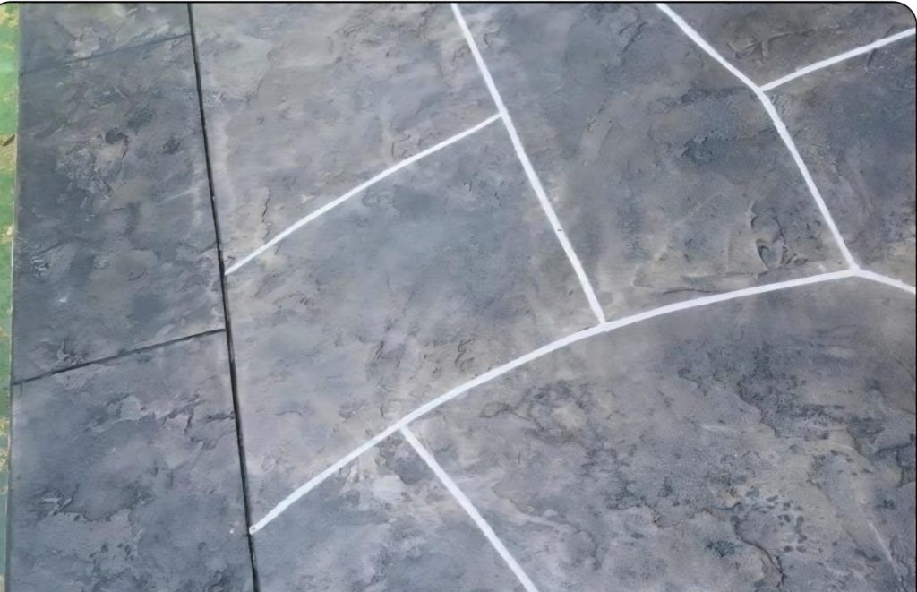 Gray stone pavement with white curved and straight grout lines forming geometric patterns.